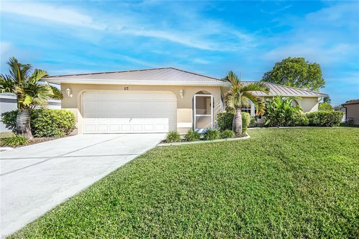 Single story home with a garage and a front lawn