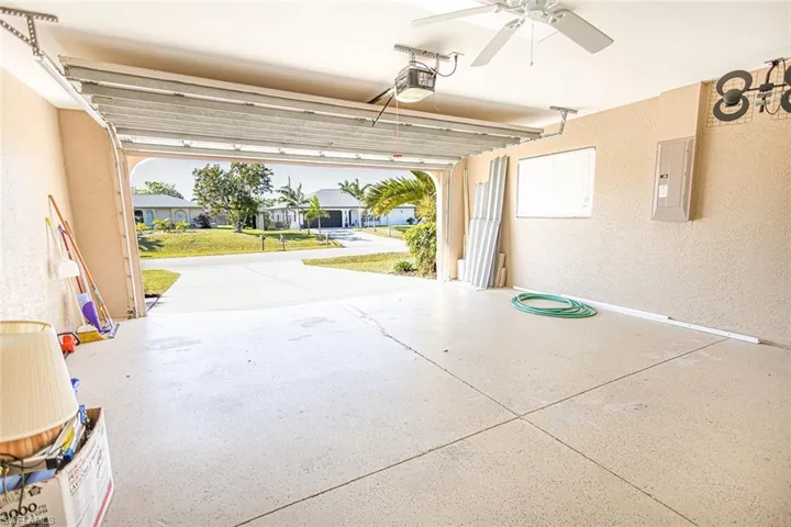 Garage featuring ceiling fan, a garage door opener, and electric panel