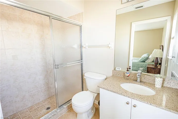 Bathroom featuring tile patterned floors, vanity, toilet, and a shower with door