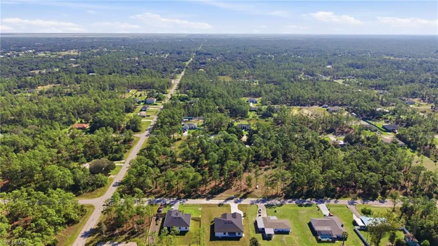 Aerial view showcasing four modern residences situated on expansive, manicured grounds with mature tree coverage