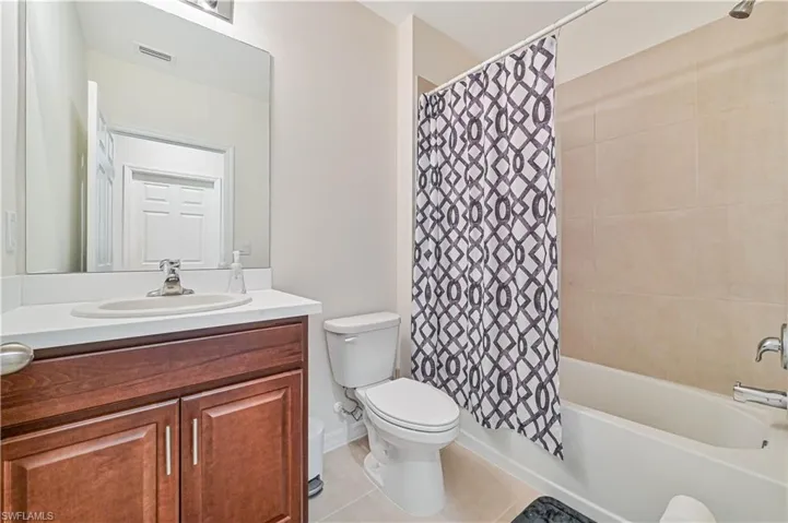 Full bathroom featuring vanity, shower / bath combo with shower curtain, toilet, and tile patterned floors