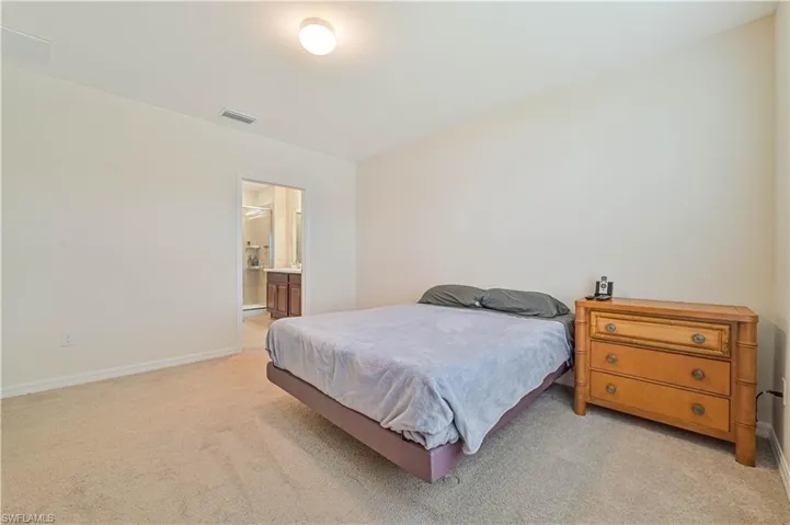 Bedroom featuring light carpet and ensuite bath