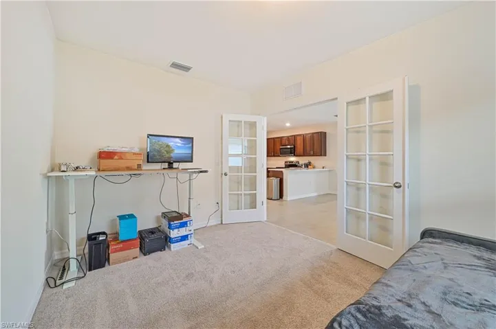 Den featuring french doors and light carpet