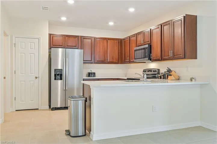 Kitchen with sink, stainless steel appliances, light tile patterned flooring, and kitchen peninsula