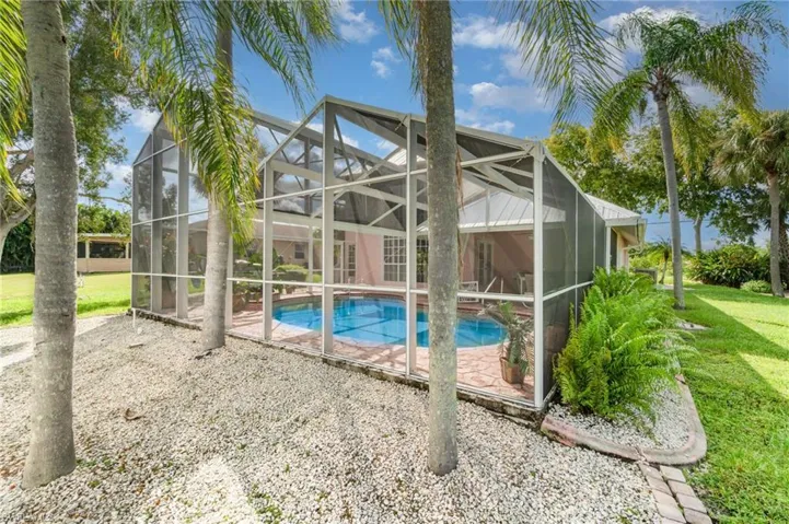 Outdoor pool with a sunroom, glass enclosure, and a lawn