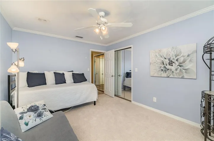 Bedroom with ornamental molding, carpet floors, a ceiling fan, and a closet