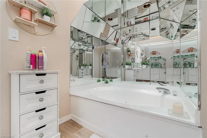 Full bath with a garden tub, vanity, and light wood-style floors