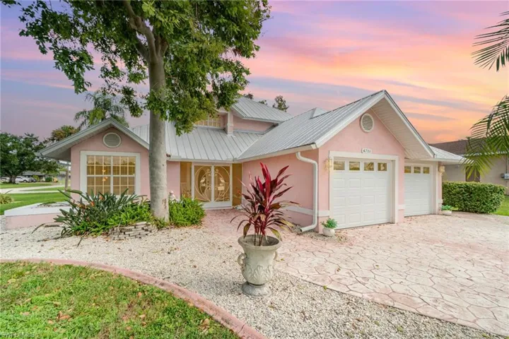 View of front of house with stucco siding, a metal roof, an attached garage, and decorative driveway