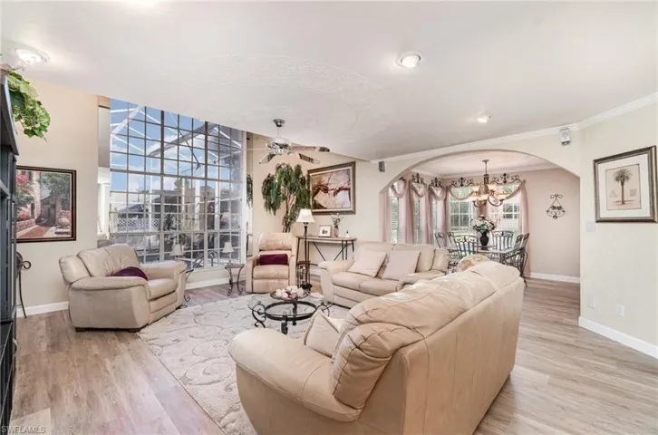 Living room featuring arched walkways, light wood-style flooring, a chandelier, ceiling fan, and recessed lighting