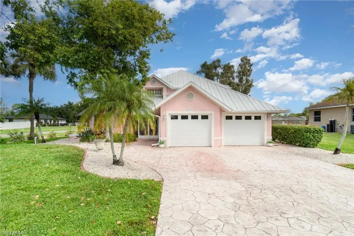 View of front facade with a front yard, decorative driveway, a metal roof, an attached garage, and stucco siding