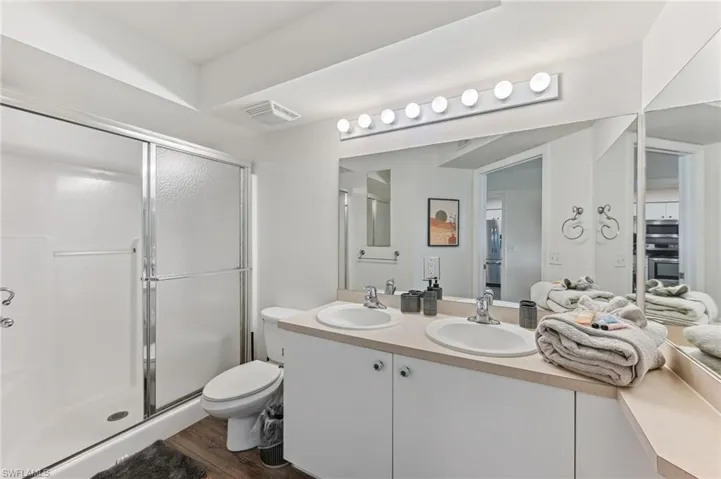 Bathroom featuring double vanity, a shower stall, and dark wood finished floors