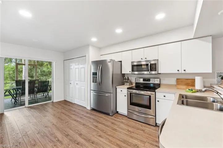 Kitchen featuring stainless steel appliances, light countertops, white cabinets, light wood-style flooring, and recessed lighting