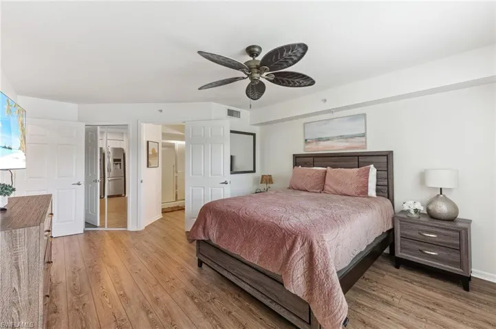 Bedroom with ceiling fan, light wood-type flooring, stainless steel fridge with ice dispenser, and a closet