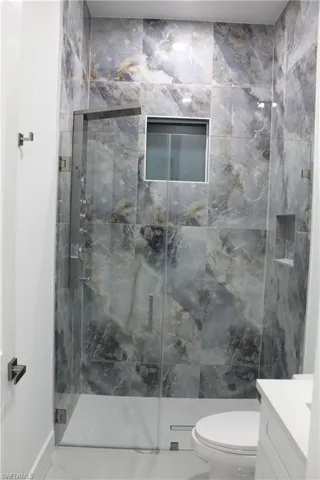 Full bathroom with vanity and a marble finish tile shower