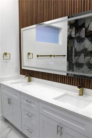 Full bathroom with double vanity, light marble finish floors, and a marble finish shower