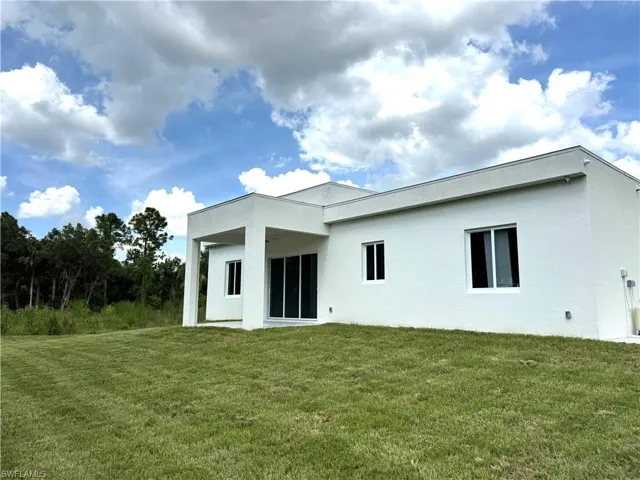 Rear view of house featuring a lawn, stucco siding, and ceiling fan