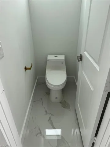 Master one unit toilet room featuring baseboards and marble look tile flooring