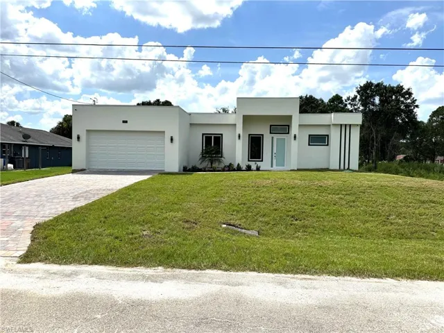 Modern home with decorative driveway, a front lawn, stucco siding, and a garage