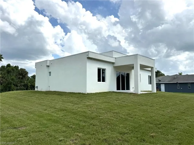 Rear view of property featuring a patio, stucco siding, and a lawn