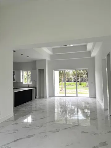 Empty room with light marble finish floors and a tray ceiling