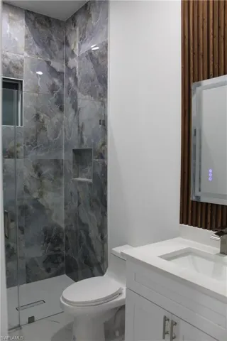 Bathroom featuring vanity, a marble finish tile shower, and marble finish floors