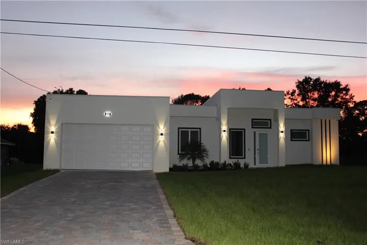 View of front facade featuring decorative driveway, an attached garage, stucco siding, and a front yard