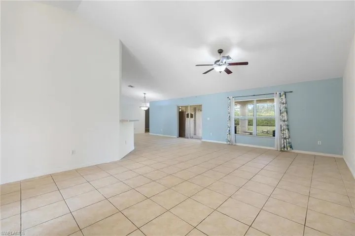 Empty room featuring vaulted ceiling, light tile patterned floors, and ceiling fan