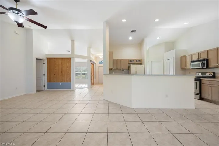 Kitchen featuring light tile patterned flooring, appliances with stainless steel finishes, high vaulted ceiling, and ceiling fan