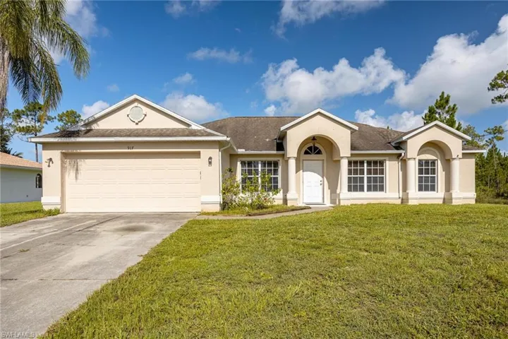 Ranch-style house featuring a garage and a front lawn