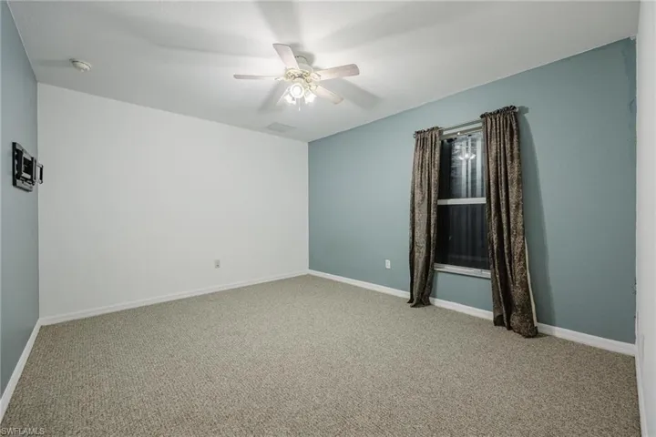 Carpeted empty room with ceiling fan