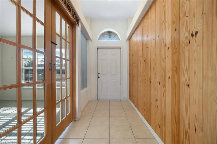 Entryway with wooden walls, a wealth of natural light, and light tile patterned floors
