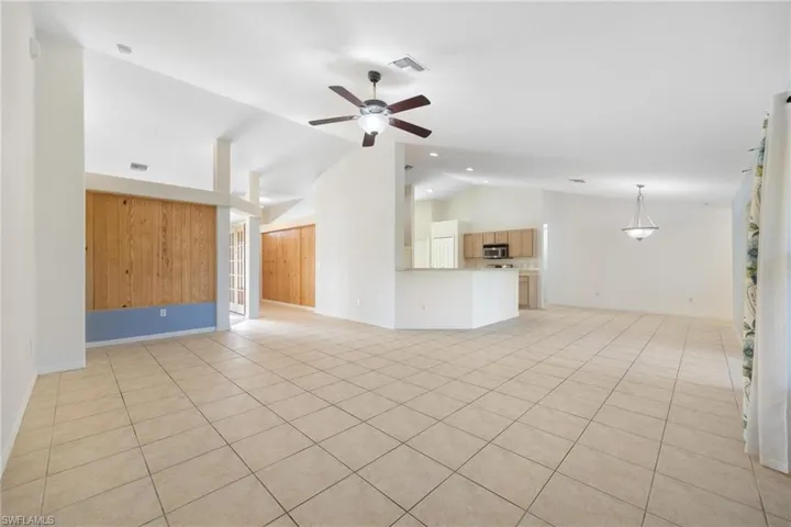 Unfurnished living room featuring high vaulted ceiling, ceiling fan, and light tile patterned floors