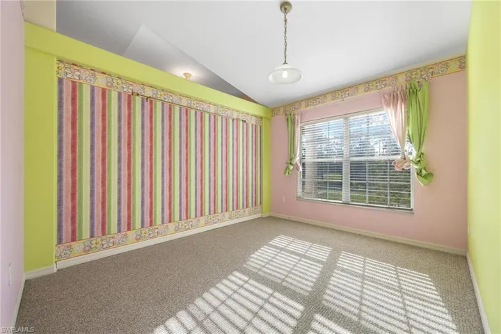 Carpeted spare room with vaulted ceiling