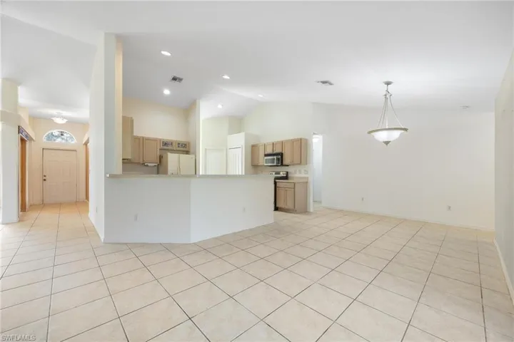Unfurnished living room with vaulted ceiling and light tile patterned floors