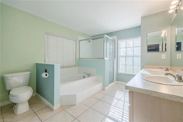 Full bathroom featuring tile patterned floors, independent shower and bath, toilet, and dual bowl vanity