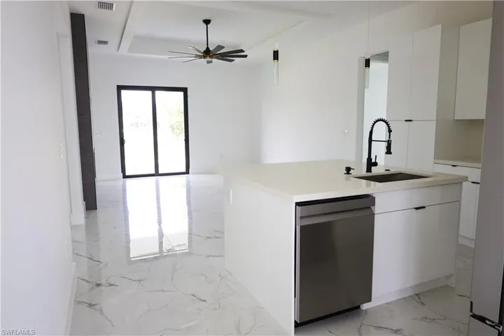 Kitchen featuring sink, white cabinetry, light tile patterned flooring, dishwasher, and ceiling fan