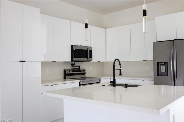Kitchen featuring hanging light fixtures, stainless steel appliances, and white cabinets