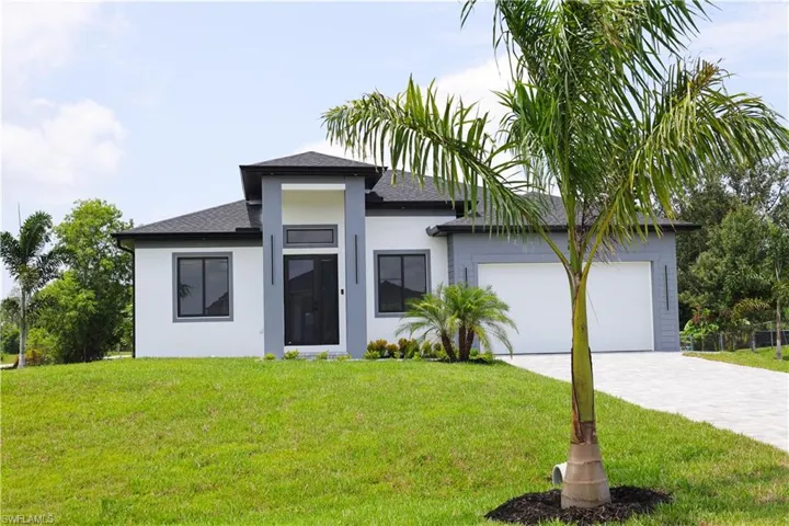 View of front of home with a garage and a front yard