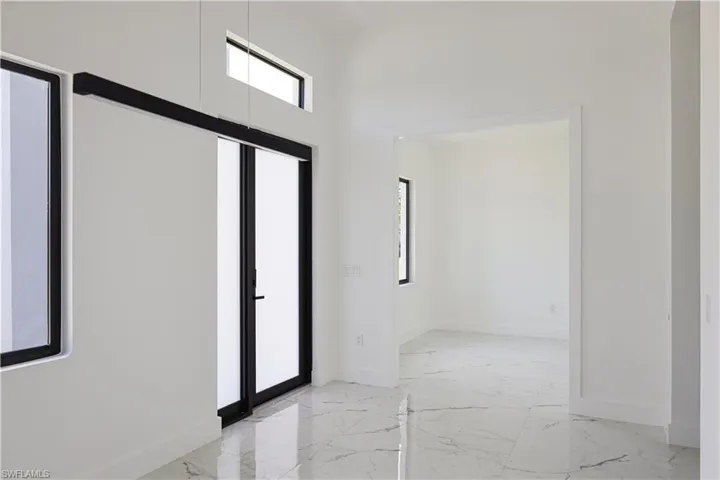 Empty room with light tile patterned floors and a high ceiling