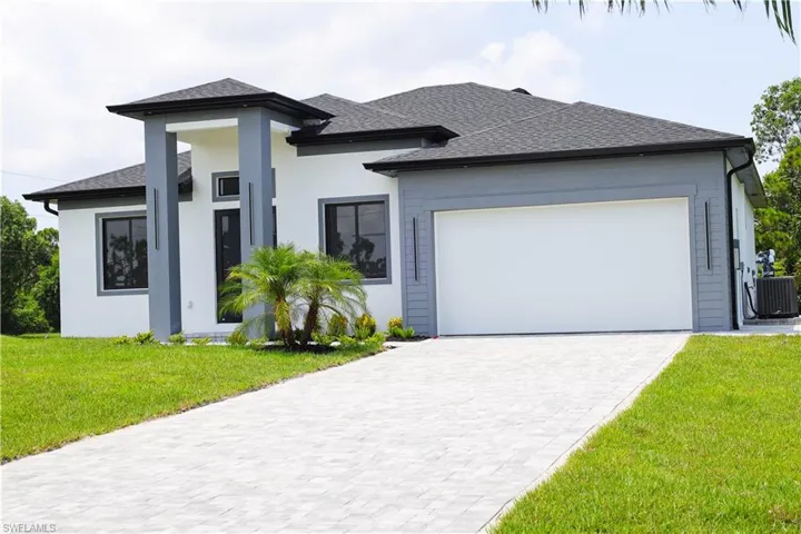 View of front of property featuring central AC unit, a garage, and a front yard