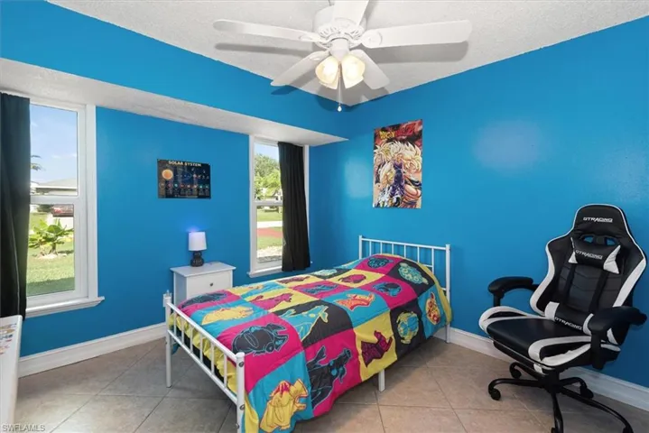 Bedroom featuring tile patterned floors, a textured ceiling, and ceiling fan