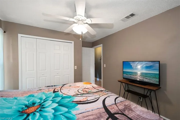 Bedroom with a textured ceiling, a closet, and ceiling fan