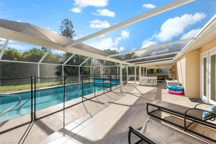 Swimming pool featuring a patio area, a sunroom, a lanai, and french doors