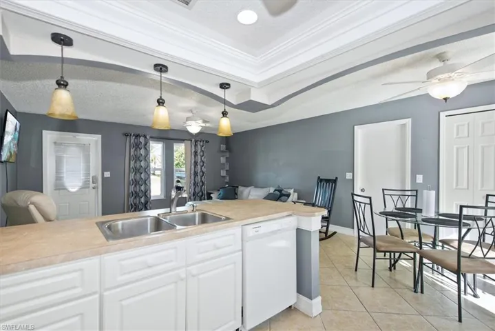 Kitchen featuring a ceiling fan, light countertops, dishwasher, light tile patterned flooring, and a textured ceiling