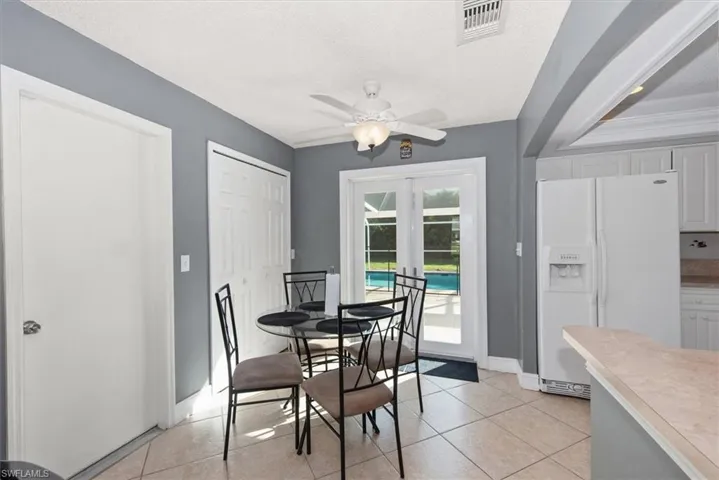Dining space featuring light tile patterned floors, a textured ceiling, french doors, and ceiling fan