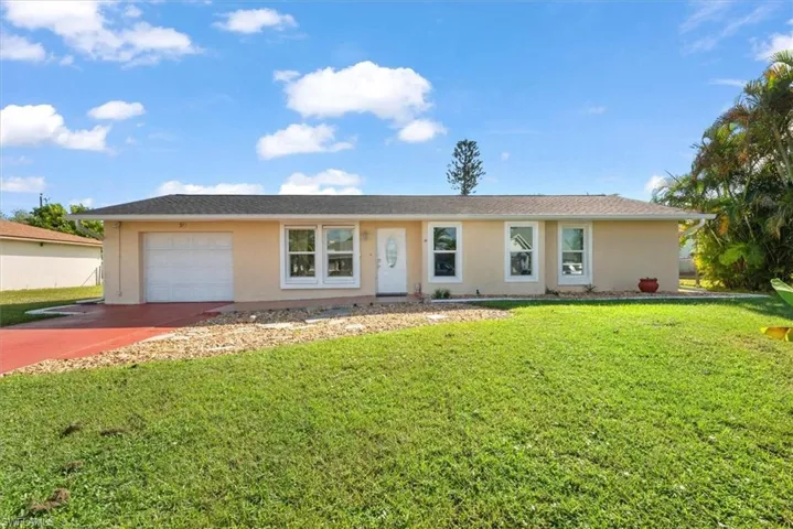 Single story home with a front lawn, driveway, and stucco siding