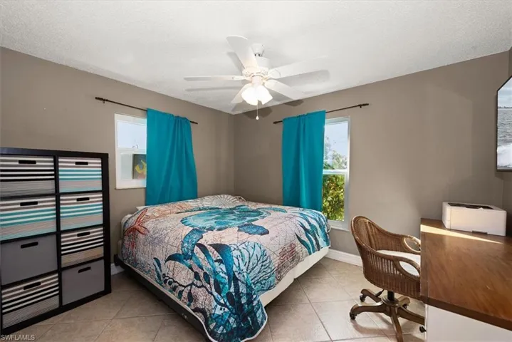 Bedroom with light tile patterned floors, a ceiling fan, a textured ceiling, and a desk