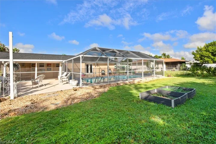 Back of property with a sunroom, a vegetable garden, a patio, and glass enclosure