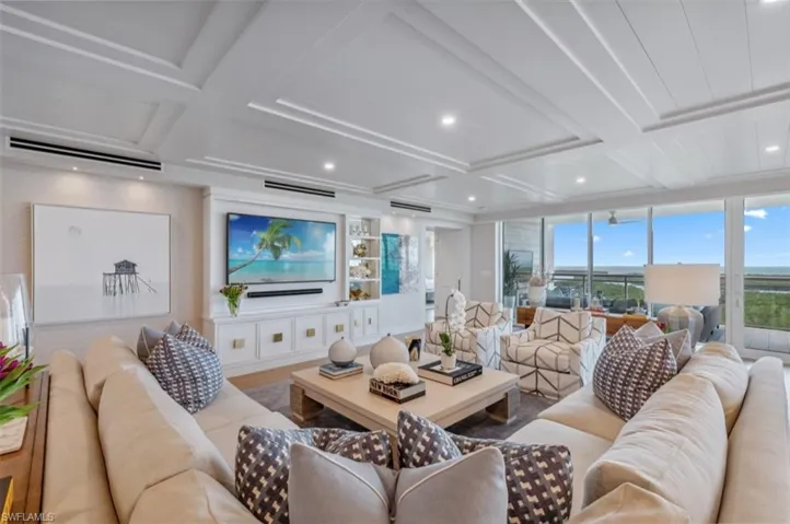 Living area with coffered ceiling, beam ceiling, recessed lighting, a wall unit AC, and wood finished floors