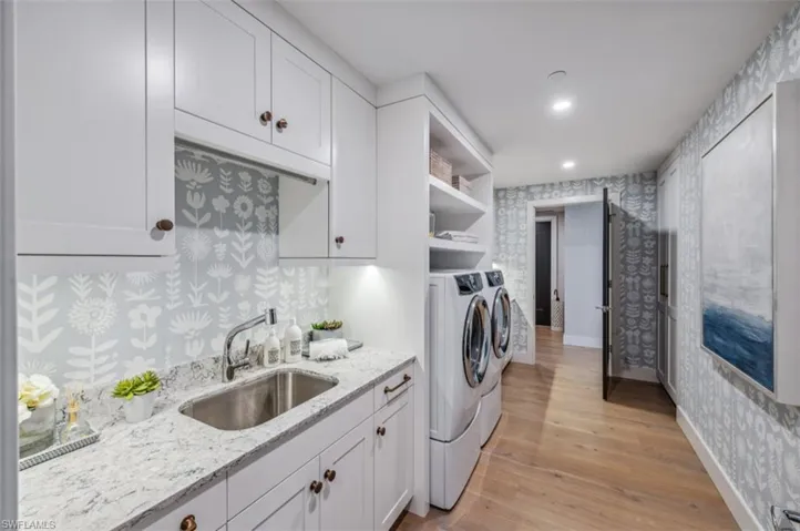 Laundry area with wallpapered walls, light wood-style flooring, washer and clothes dryer, and recessed lighting